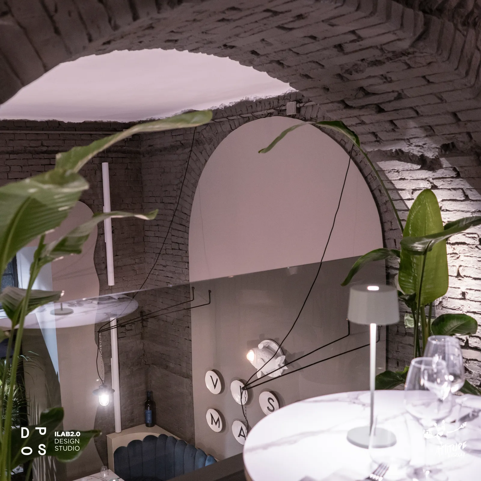 Arco in mattoni con tavolo in marmo e lampada da tavolo a Krudo